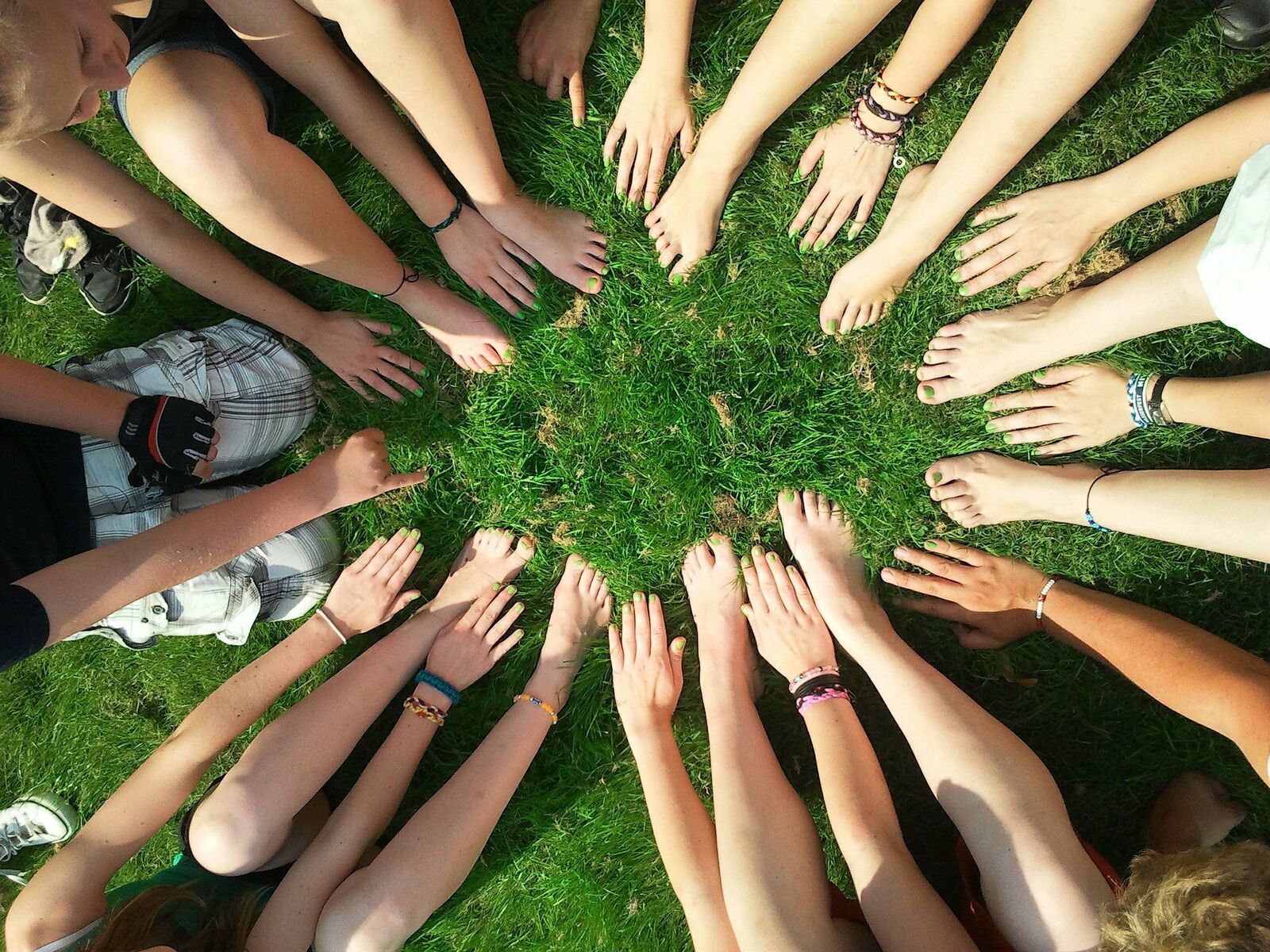 Eine Gruppe von Menschen legen Hände und Füße in einen Kreis als Zeichen der Gemeinschaft