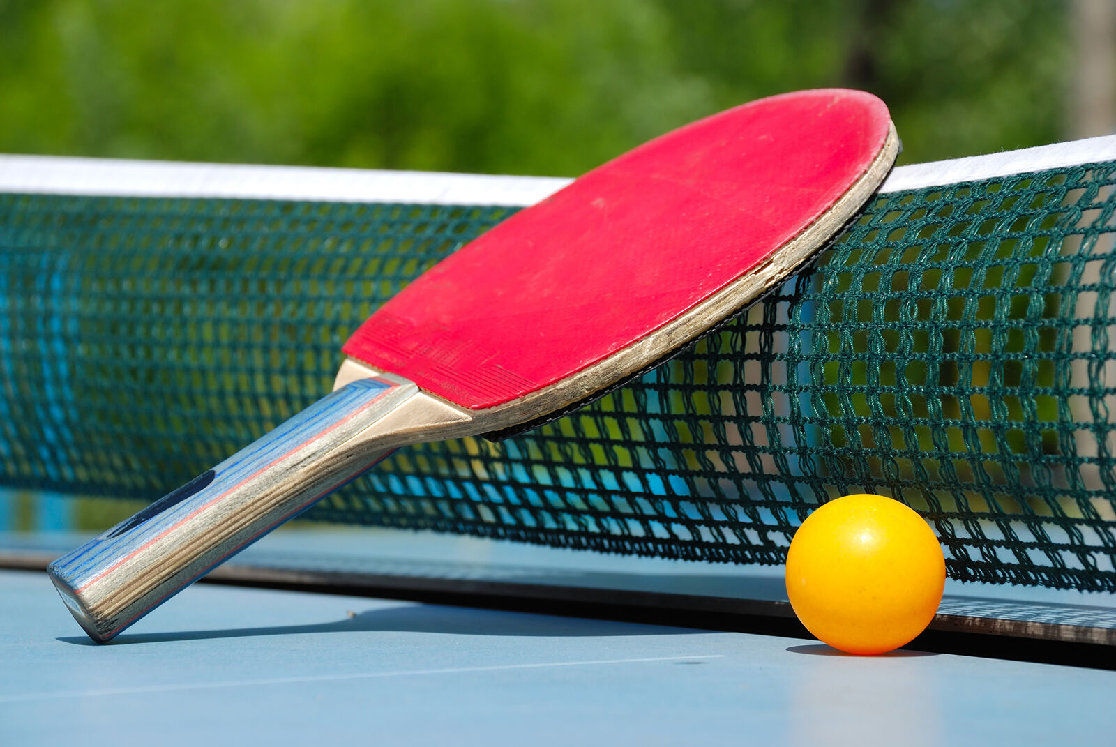 Tischtennisschläger mit Ball auf Platte