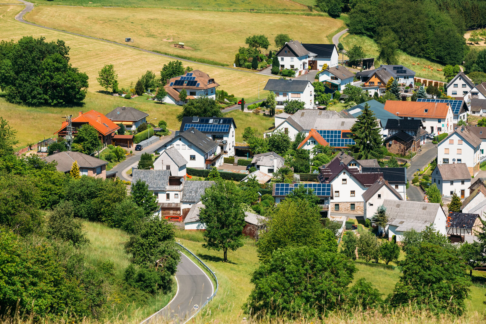 Blick von oben auf eine Siedlung die gemischt ist aus Häusern mit Photovoltaik auf dem Dach und ohne.
