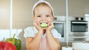 Kind isst Gemüse in der Küche
