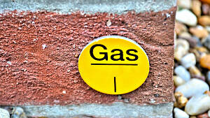 Eine gelbe Plakette mit der Aufschrift Gas vor einer roten Ziegelwand