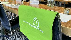 Ein Jutebetel vom Verband Wohneigentum hängt über einem Stuhl in einem Konferenzraum.