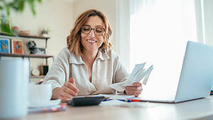 Frau rechnet am Schreibtisch mit PC