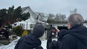 Drei Menschen stehen vor einem verschneiten Haus und machen eine Aufnahme mit der Wärmebildkamera.
