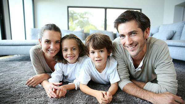 Themenbild: Familie auf Teppich im Wohnzimmer Themenbild: Familie auf Teppich im Wohnzimmer