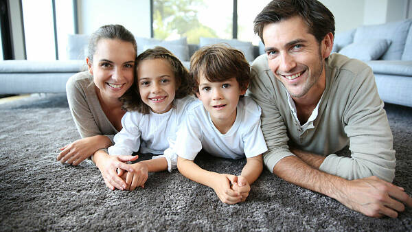 Themenbild: Familie auf Teppich im Wohnzimmer