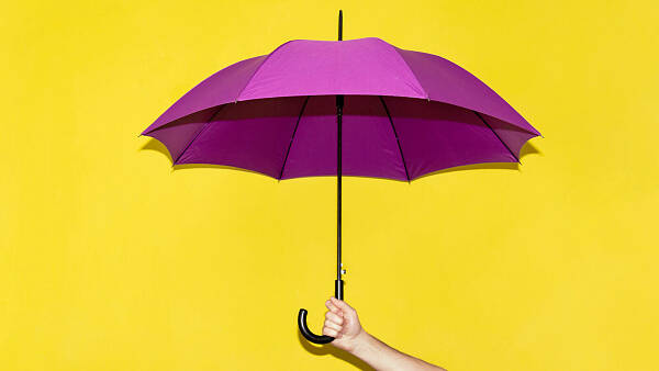 Themenbild: Ein Hand hält einen violetten Regenschirm vor einem gelben Hintergrund