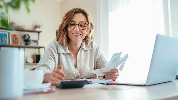 Themenbild: Frau rechnet am Schreibtisch mit PC