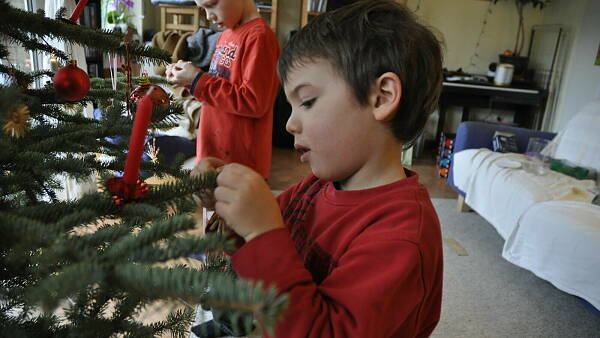 Themenbild: Kind schmückt Weihnachtsbaum
