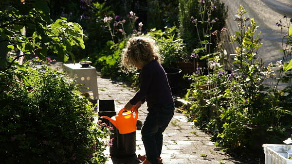 Themenbild: Kind mit Gießkanne im Garten