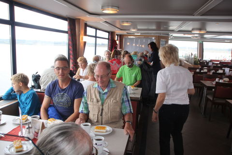 Die Teilnehmer lassen sich Kaffee und Kuchen auf dem Schiff schmecken.