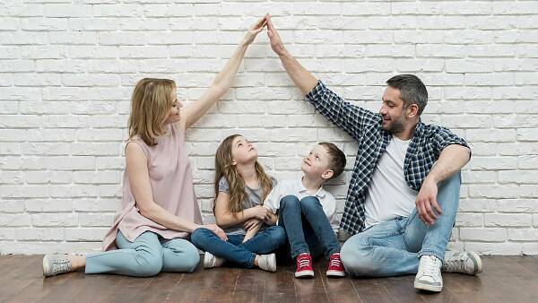 Themenbild: Familie auf dem Boden sitzend vor einer Wand