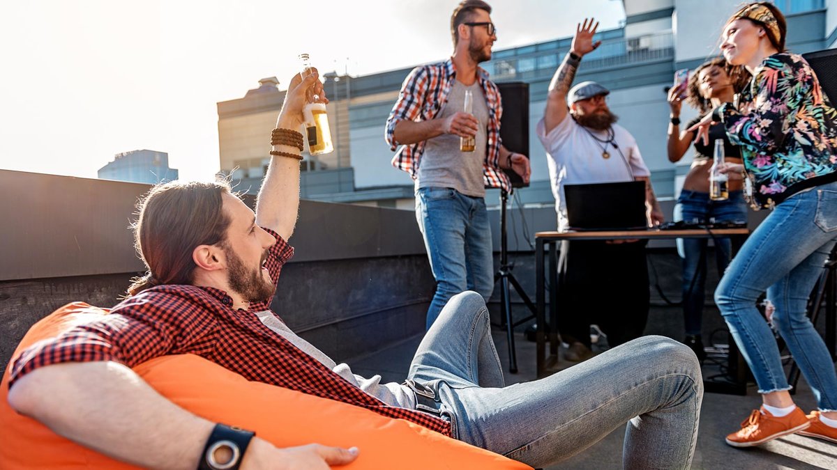junge Leute feiern auf einem Balkon mit Alkohol