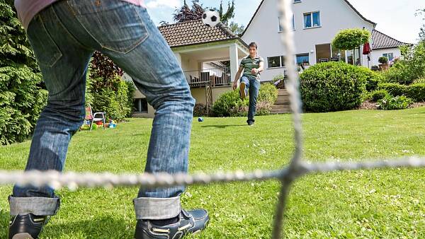 Themenbild: Vater und Kind spielen Fußball im Garten
